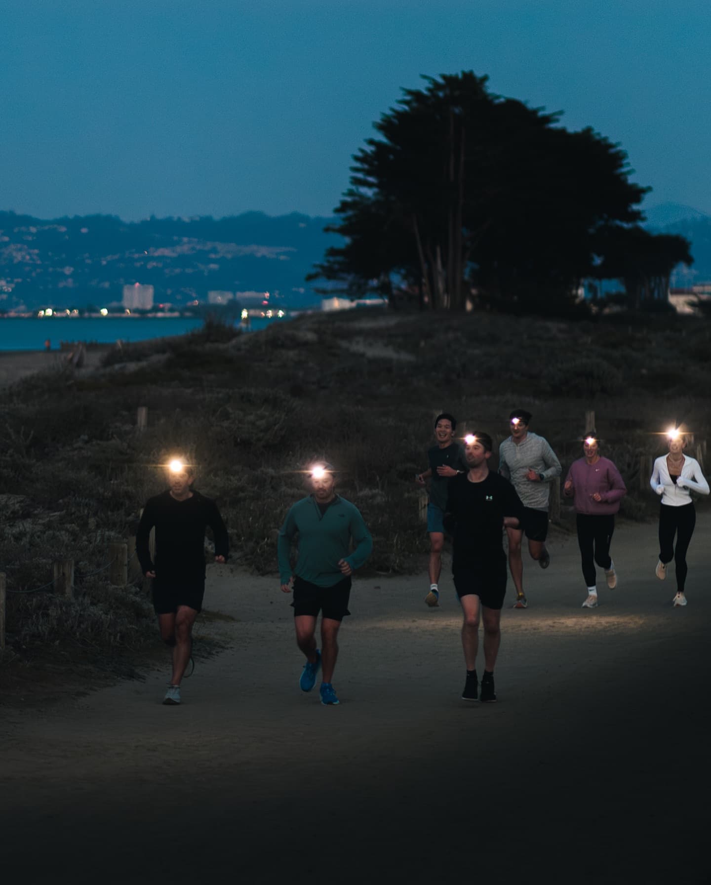 Runners from Marina Run Club gathering at dusk with San Francisco Bay, Alcatraz Island, and the Golden Gate Bridge visible in the background